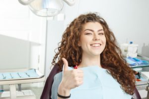 young woman giving thumbs up before dental implant surgery 